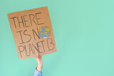 Stop climate change concept. Hand with denim jacket holding a there is no planet b cardboard sign over turquoise background with copy space