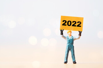 Wall Mural - Worker man holding yellow paper with 2022 year for preparation happy new year and start new business plan.