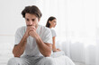 © Prostock-studio - Depressed young caucasian husband with stubble sits on bed and sad, ignoring offended lady in bedroom