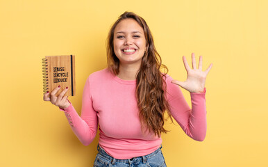 Wall Mural - hispanic pretty woman smiling and looking friendly, showing number five. recycle concept