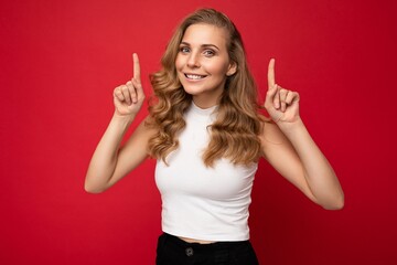 Wall Mural - Portrait photo of young beautiful pretty self-confident assertive cool happy positive smiling blonde woman with sincere emotions wearing stylish white top isolated over red background with free space