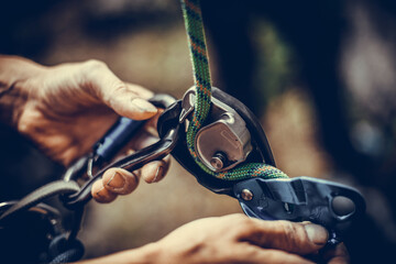 Man's hands operating a rock climbing belaying device