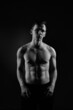 © ksi - Black and white portrait of an athletic guy on a black background.
