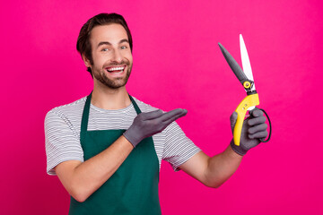 Wall Mural - Photo of florist shop owner man palm demonstrate shears wear gloves apron t-shirt isolated pink color background