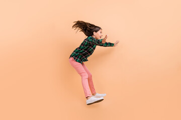 Sticker - Photo of funky impressed school girl dressed checkered clothes smiling jumping high catching empty space isolated beige color background