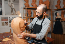 Craftsman Carving Wooden Sculpture In Workshop