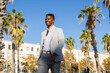 © ADDICTIVE STOCK - Serious black man in formal wear standing among palms