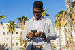 © ADDICTIVE STOCK - Smiling black man in formal wear using smartphone