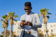 © ADDICTIVE STOCK - Smiling black man in formal wear using smartphone