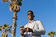 © ADDICTIVE STOCK - Smiling black man in formal wear using smartphone