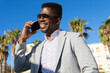 © ADDICTIVE STOCK - Smiling black man in formal wear speaking on smartphone