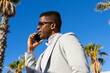 © ADDICTIVE STOCK - Smiling black man in formal wear speaking on smartphone