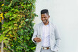 © ADDICTIVE STOCK - Smiling black man in stylish clothes browsing smartphone