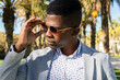 © ADDICTIVE STOCK - Serious black man adjusting stylish sunglasses in park