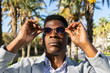 © ADDICTIVE STOCK - Serious black man adjusting stylish sunglasses in park