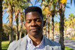 © ADDICTIVE STOCK - Relaxed black businessman sitting in tropical park