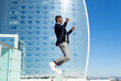 © ADDICTIVE STOCK - Excited black man jumping high against modern skyscraper