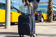 © ADDICTIVE STOCK - Anonymous black businessman with suitcase on sidewalk past taxi cars