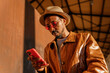 © ADDICTIVE STOCK - Stylish black man browsing smartphone on street