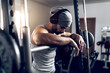 © ADDICTIVE STOCK - Shirtless man adjusting headphones before training with barbell