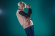 © qunica.com - Young adult man in casual outfit wear looking at camera, holding skateboard near face and standing at studio on blue background