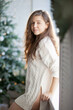 © Dina - Beautiful young caucasian brunette woman standing near window and decorated christmas tree at home on holiday season