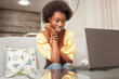 © Valeriia - African Black American Woman sits in front of laptop and watches a movie, a love letter, a sweet woman smiling, sits.