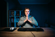 © bodnarphoto - Guy gamer sits in a headset at home at night at the computer and prays for his team looking into the camera with despair on his face.