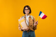 Travel and student exchange. Happy young woman in glasses with notebooks, backpack, holding small flag of France