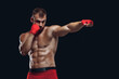 © satyrenko - Front view of a sporty man in boxing gloves practicing fighting techniques isolated on black background