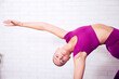 profesora de yoga y pilates mujer joven hace posiciones y posturas en un gimnasio o estudio sobre una esterilla y con un balon grande hinchable para trabajar en gimnasio ejercicios practicos