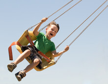 Joy Thrill And Fun Are The Emotions Of A Young Boy Swinging On A Ride At The Local Carnival.