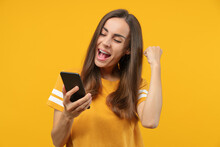 Portrait Of Euphoric Soccer Fan Girl Celebrating Her Favourite Team Victory And Money Win After Betting At Bookmaker's Mobile Application, Making Winner's Gesture Clenching Her Fist