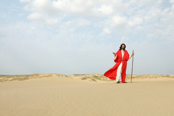 Jesus Christ walking with stick in desert. Space for text