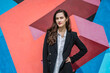 © Cavan Images - Confident young female manager standing near graffiti wall