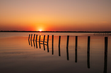 Wall Mural - Beautiful red and orange sunset over the sea. The sun goes down over the sea. An old sea pier in orange sunset light