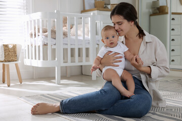 Wall Mural - Happy young mother with her baby in nursery. Space for text