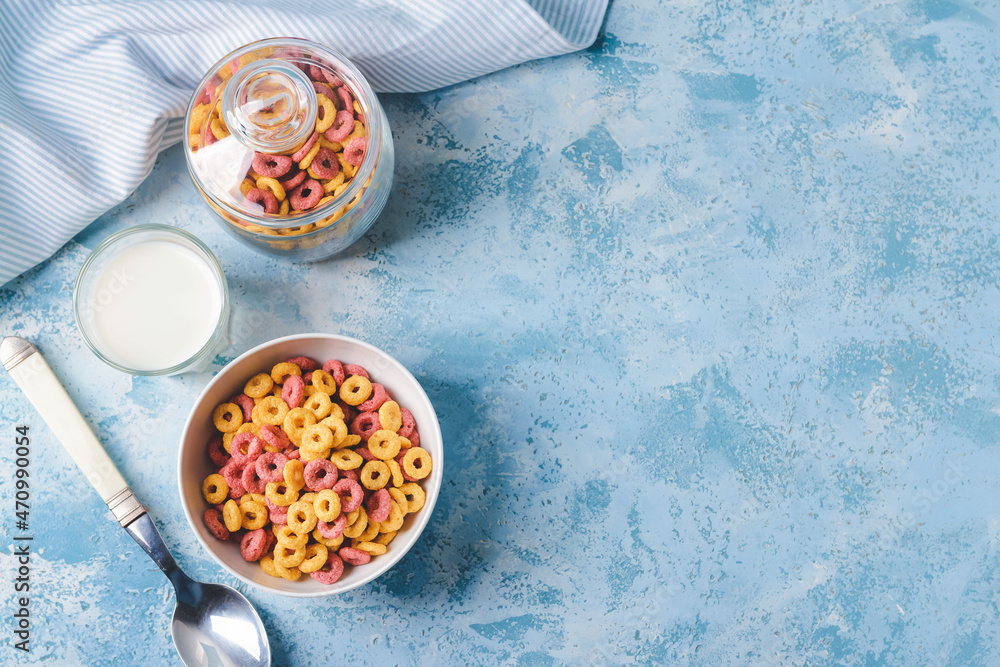 Crunchy corn flakes rings and milk on color background