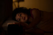 © IndiaPix - Woman watching smartphone with sleepy eyes at night while lying on bed