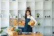 © Jirapong - Work from home. happy women selling products online Start a small business owner by using laptop computer to calculate prices and prepare for postage.