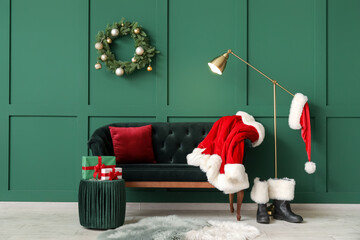 Wall Mural - Interior of stylish room with comfortable sofa, Santa Claus costume and boots near color wall