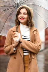 Sticker - Happy woman with umbrella walking on rainy autumn day