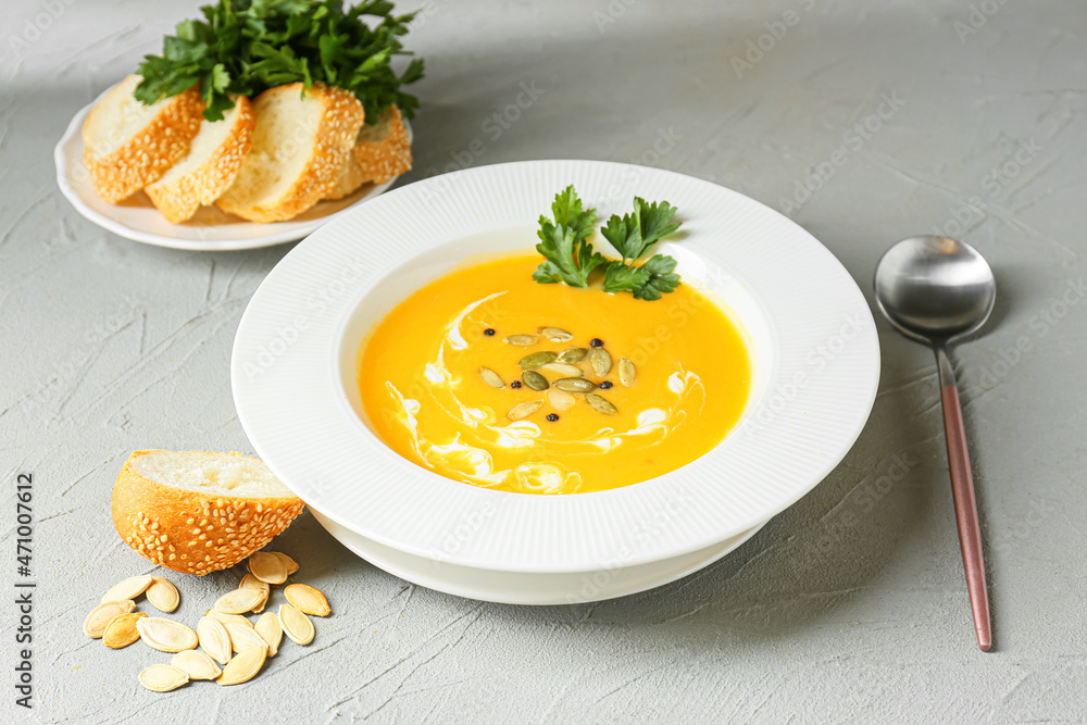Bowl with delicious pumpkin cream soup and seeds on light background
