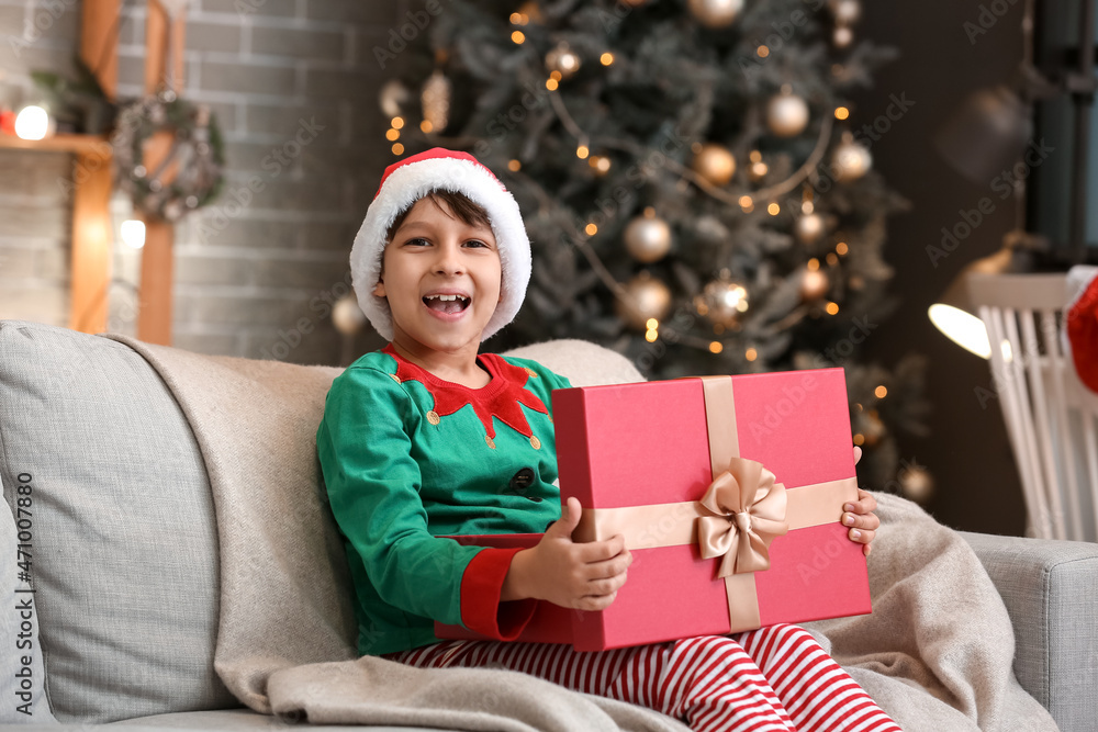 Cute little boy with gift at home on Christmas eve