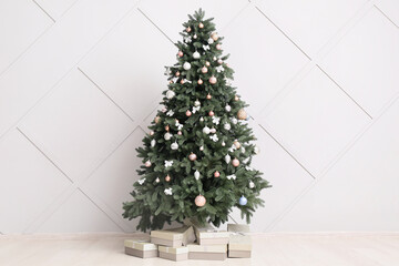 beautiful christmas tree with gift boxes near light wall
