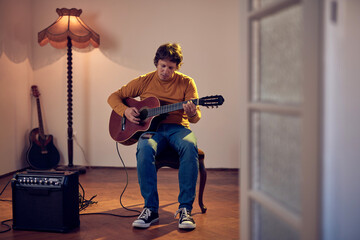 Wall Mural - Male musician playing acoustic guitar on the amplifier in retro vintage room.