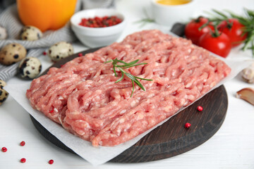 Raw chicken minced meat with rosemary and spices on white wooden table, closeup