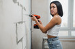 © kalinichenkod - beautiful girl in overalls with electric drill