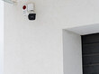 The outdoor video system is installed on house. A security camera on the outer white wall of a residential building.
