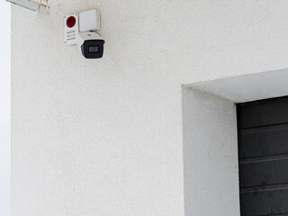 the outdoor video system is installed on house. a security camera on the outer white wall of a resid